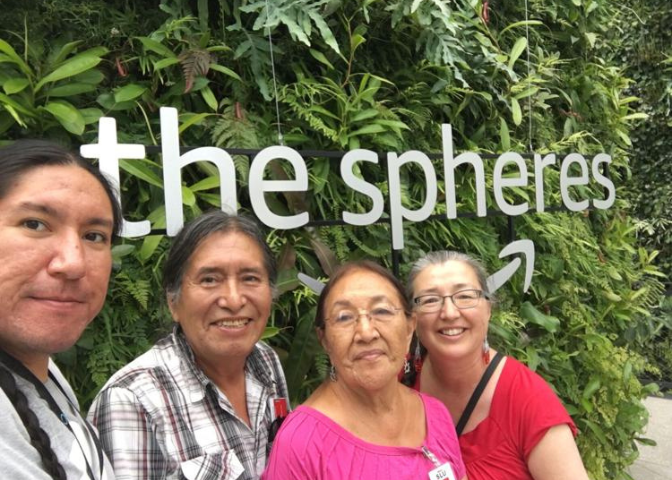 Michael Running Wolf and his family stand together in front of the Amazon Spheres sign.