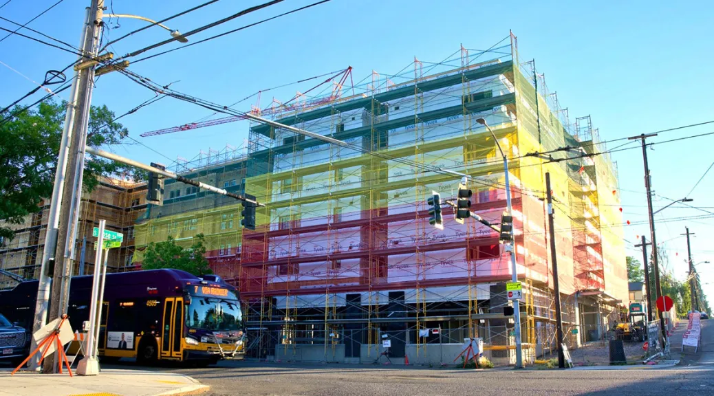 The scaffolding of a building under construction covered in colorful wrap.