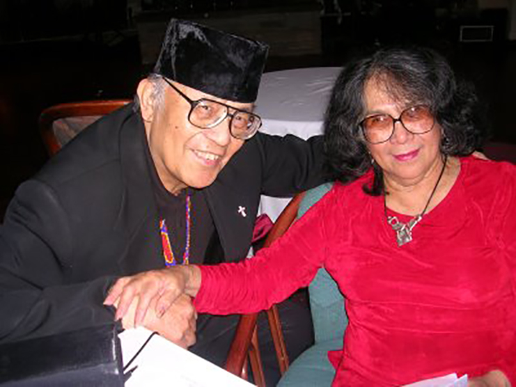 A man and woman seated at a table holding hands.