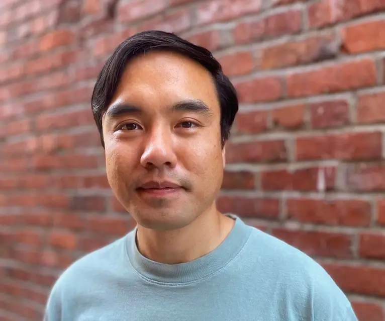 Headshot of a man in front of a brick wall