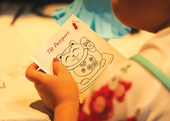 A child holds a paper "passport" for Tet with a cat on it.