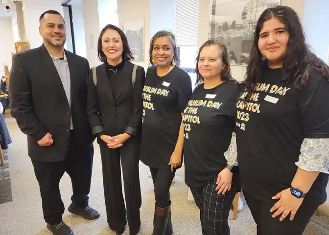 A group posing for a photo wearing shirts that say "Muslim Day at the Capitol 2023".