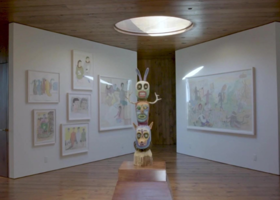 A colourful sculpture stands in the center of a room with colourful art on the walls.