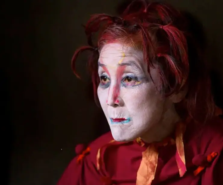 Side profile of a woman in white butoh face makeup.