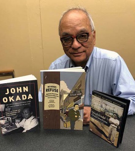 Man with glasses sits behind two books and a DVD.