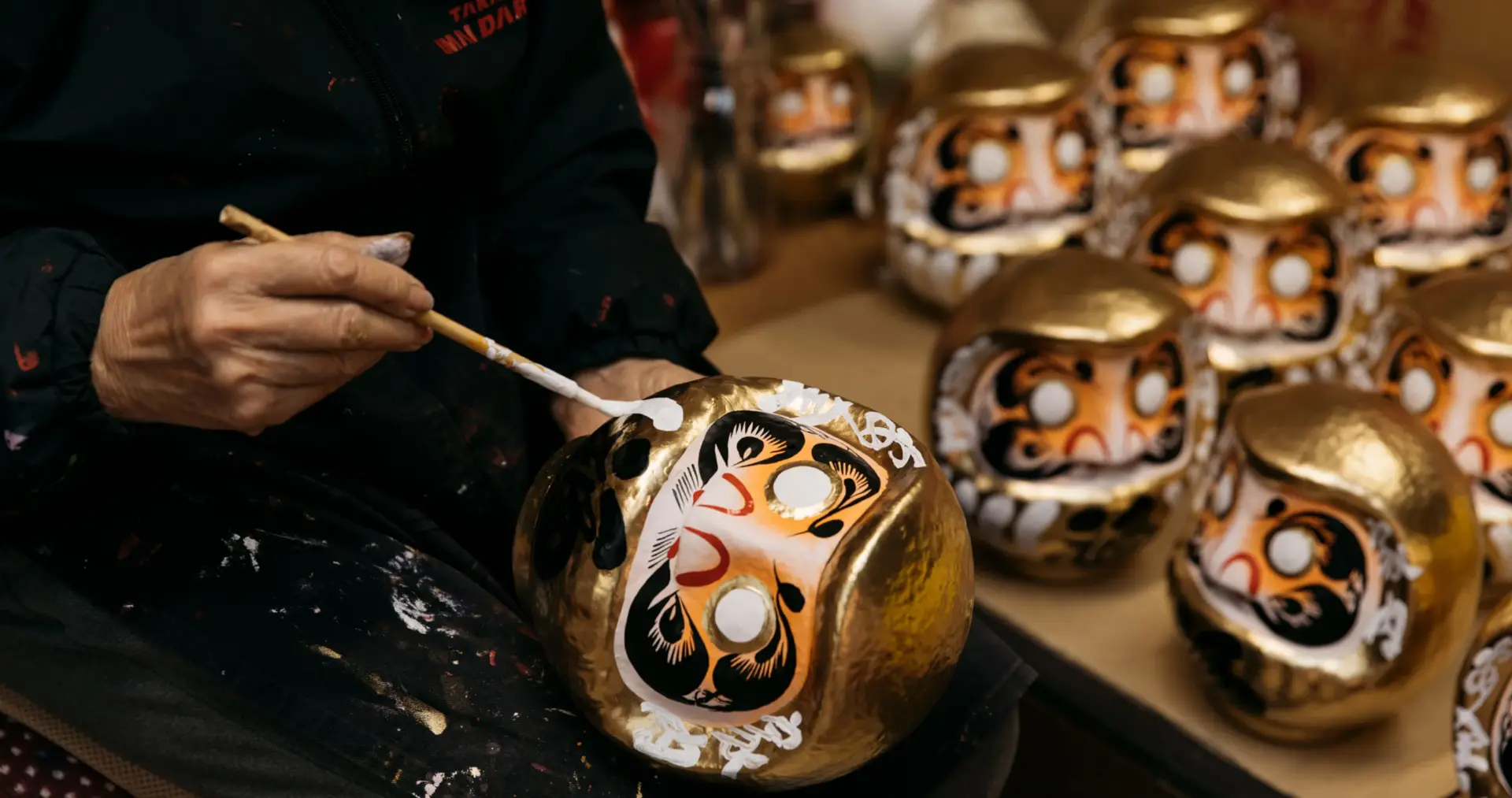 A man applies paint to the face of a daruma doll.